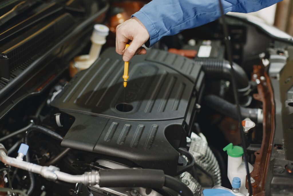 The mechanic is checking the engine oil with the help of an oil gauge.