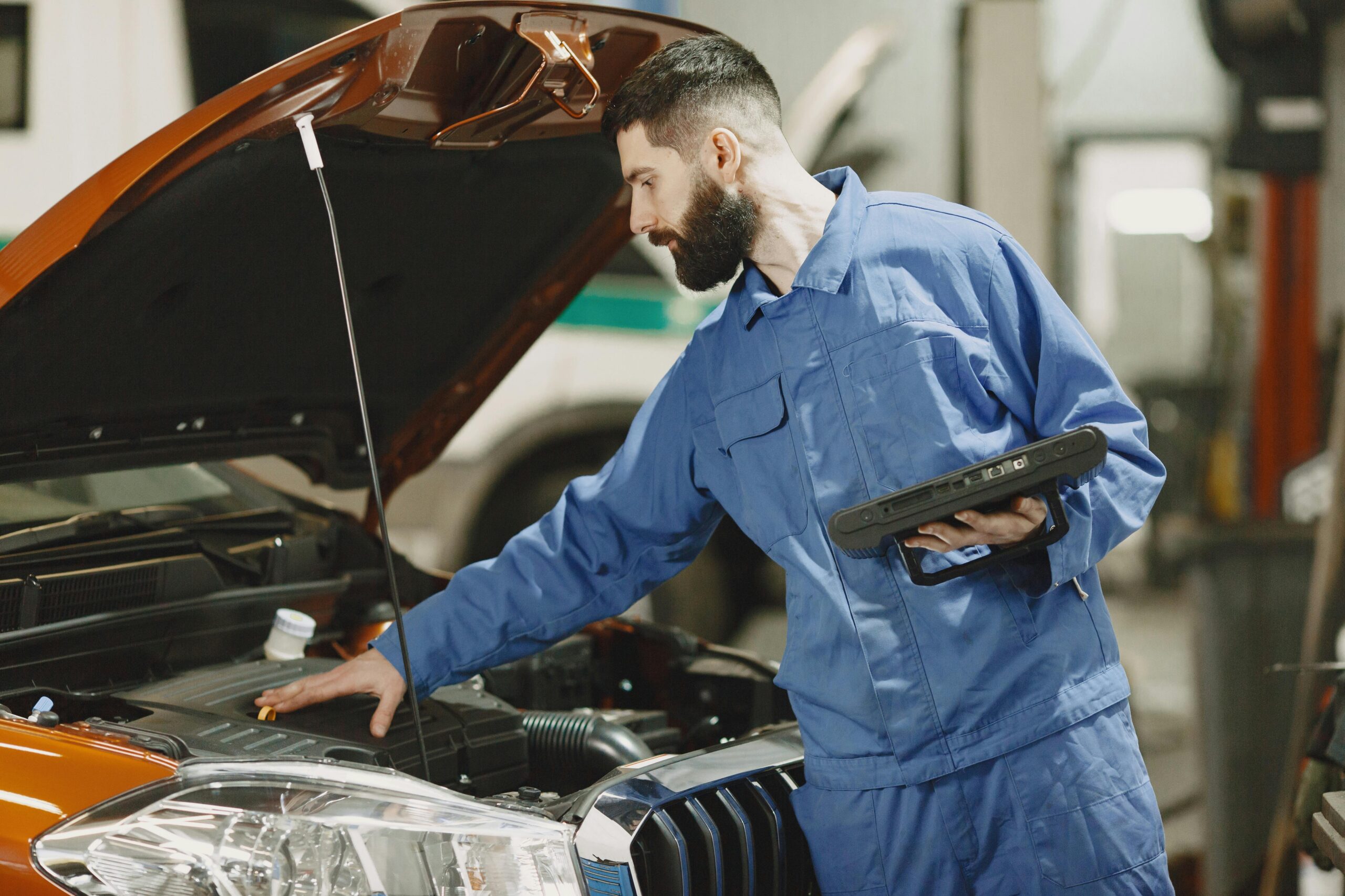 a mechanic doing a checkup by placing his hand on the car engine.